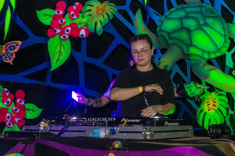 DJ tocando set com decoração neon de tartaruga